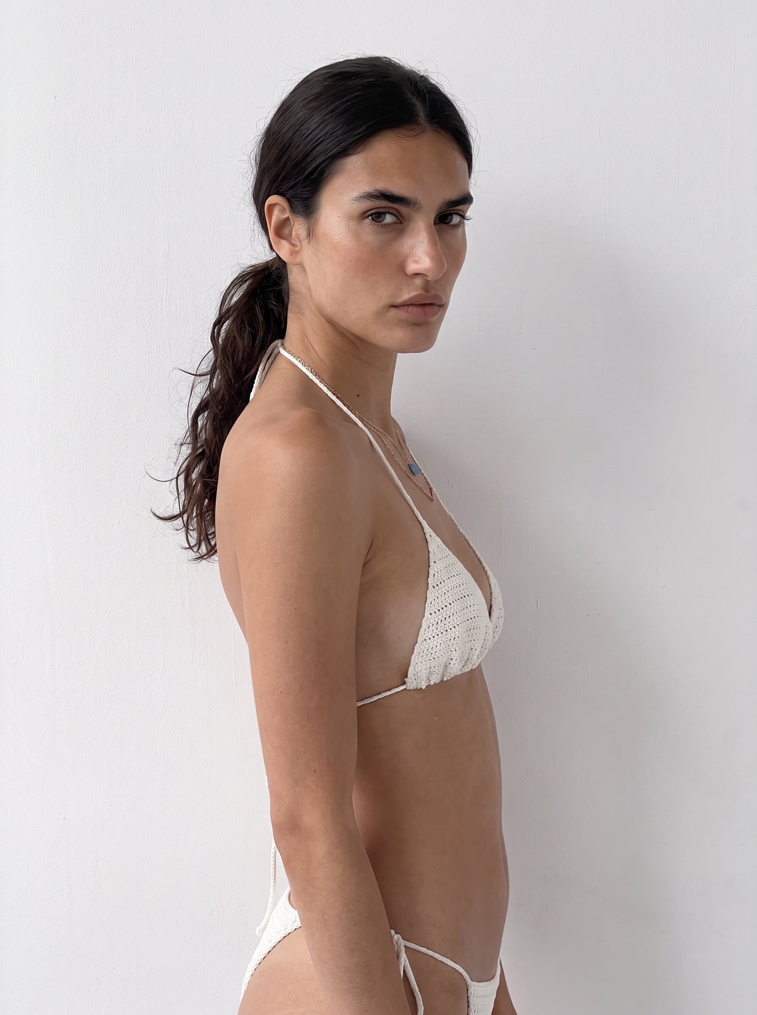 Three-quarter back view of the cream crochet bikini top showing its halter ties