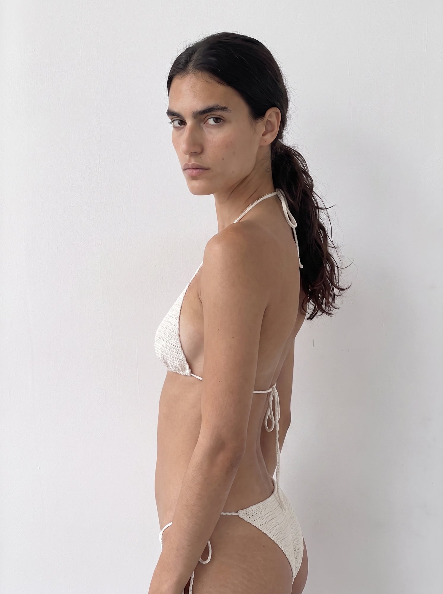 Side view of the cream crochet bikini bottom styled with the matching bikini top