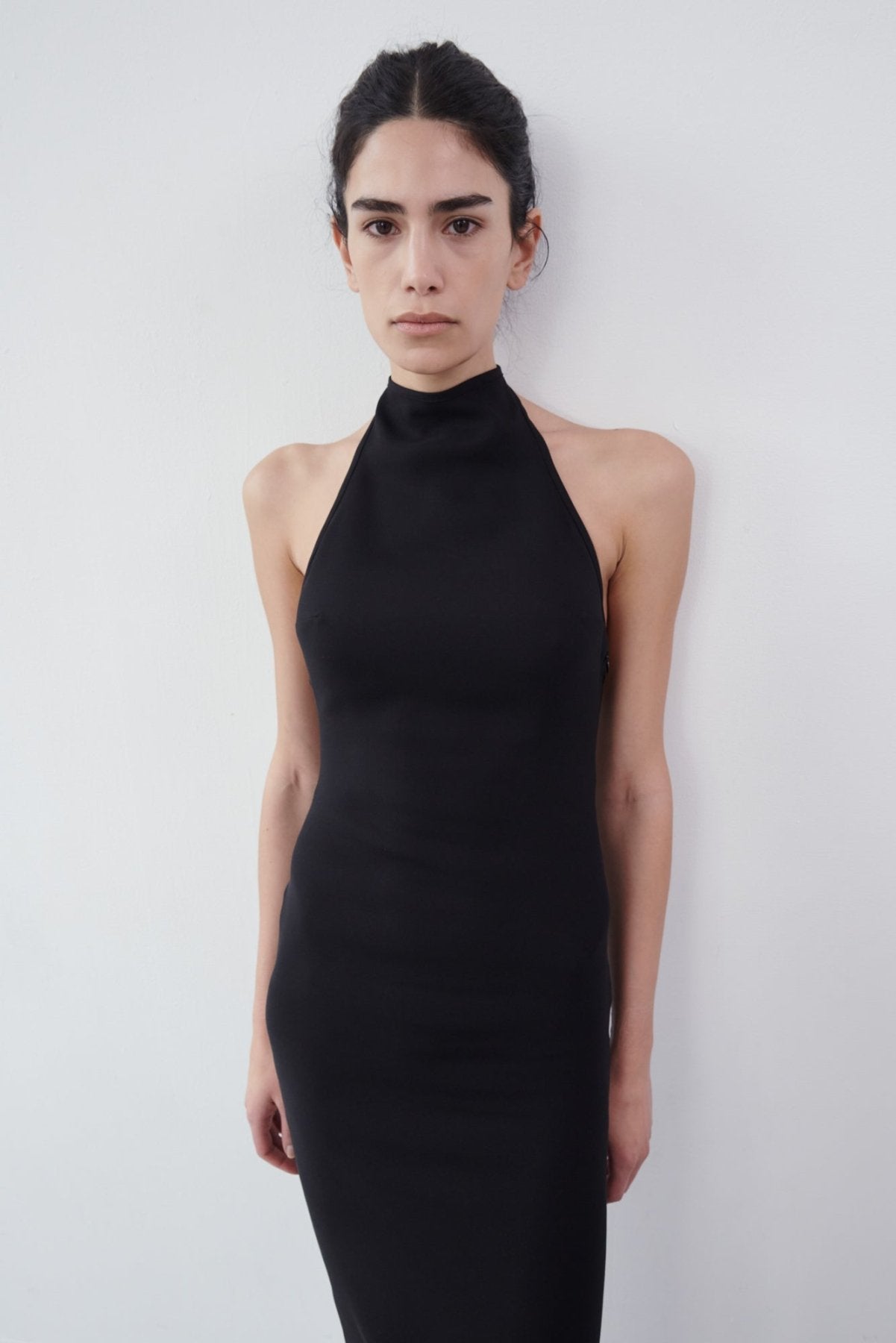 Close-up front view of a black halter maxi dress with a high neckline and smooth, fitted fabric, styled against a white background.