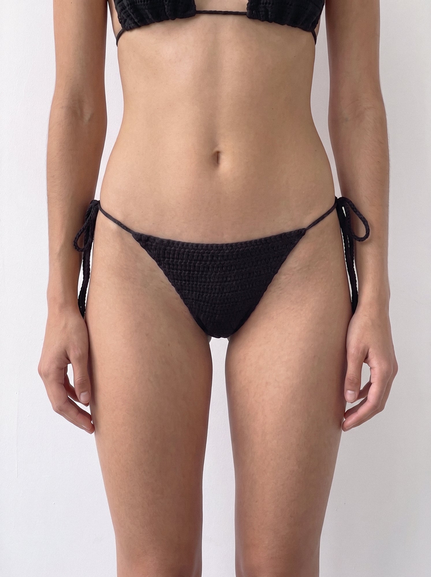 Front close-up of the handmade black crochet bikini bottom with side ties