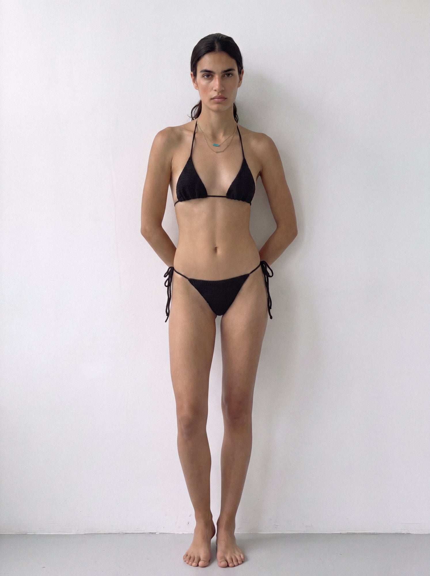 Full-length front view of the black crochet bikini bottom styled with the matching top